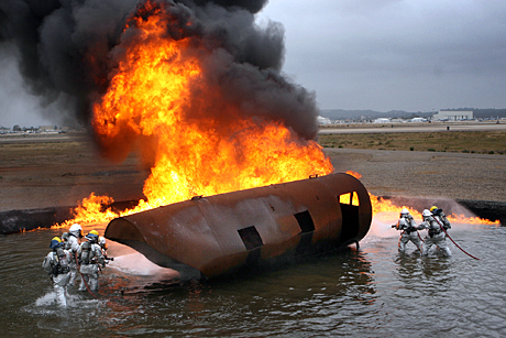 Honorable Mention Photojournalism by LCpl. Christopher O’Quin: MARINE CORPS AIR STATION MIRAMAR, Calif. - Marines with MCAS Miramar Aircraft Rescue and Fire Fighting, break off into two different groups to battle the blaze from both sides of an old aircraft cabin which is being used to simulate an aircraft crash during a controlled burn aboard the station, April 30. The Marines conduct the training on average once a month. 