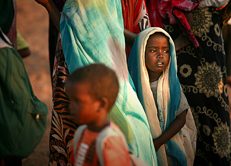 1st Place Photojournalism by Sgt. Alex Kleinsmith: A Djiboutian girl stands with her family members while Marines from 3rd Low Altitude Air Defense Battalion play soccer with men from Nagad, a village just outside downtown Djibouti, Africa. The Camp Pendleton-based Marines serve as the primary security force for Camp Lemonier, Djibouti.